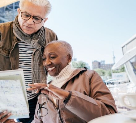 elder man and woman reviewing sheet of paper outside